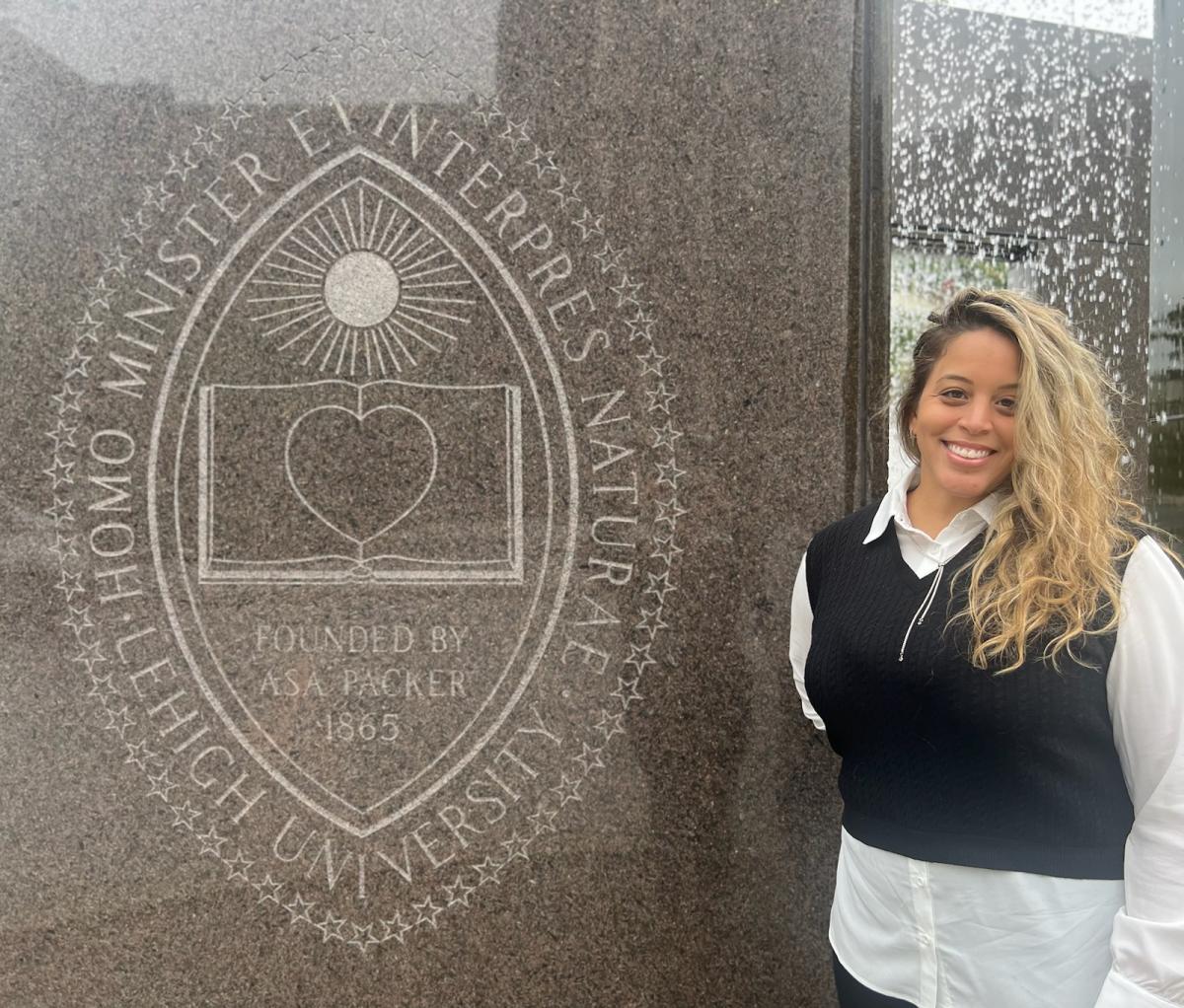 Talent Acquisition Specialist Felicia Cochrane smiles while standing next to the Lehigh fountain in front of the Alumni Memorial building