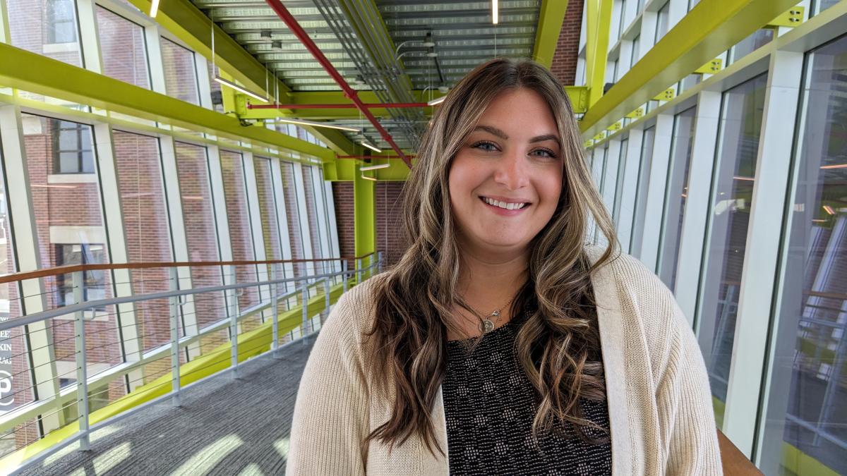 Learning Design and Development Specialist Lauren Hamory smiles as she stands in a glass-encased bridge on a sunny day in South Bethlehem near her new office in Lehigh Human Resources. 