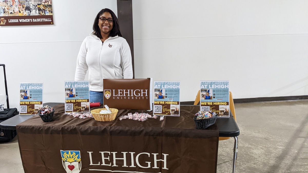 Human Resources Assistant Tashia Winn stands behind a table decorated with Lehigh University logos and containing promotional material for job opportunities at Lehigh. She was representing Lehigh at a recent event at Stabler Arena