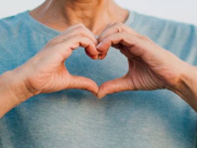 image of a person using their hands to form the heart symbol against their blue sweater