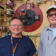 Coworkers Marshall Pysher and Dave Novogratz smile as they stand in front of Boiler #2 in the Lehigh Boiler House