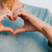 image of a person using their hands to form the heart symbol against their blue sweater
