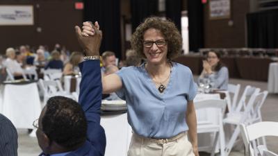 Marci Levine receives a high five from Henry Odi as she walks to the stage to receive the Inclusive Excellence Award